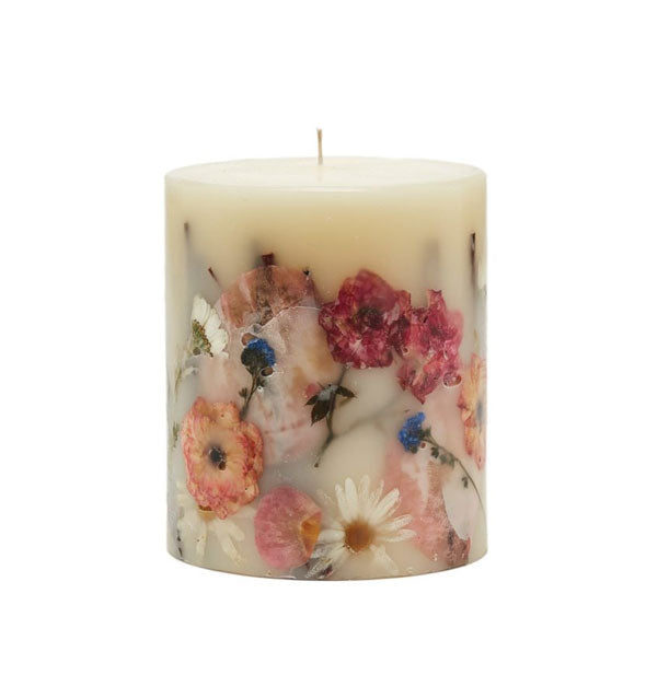White pillar candle with colorful dried flowers set in the wax