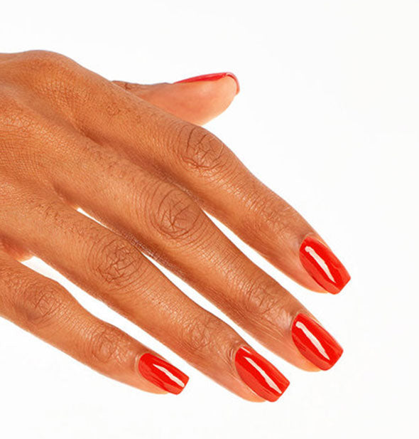 Model's hand wears a vibrant red shade of nail polish