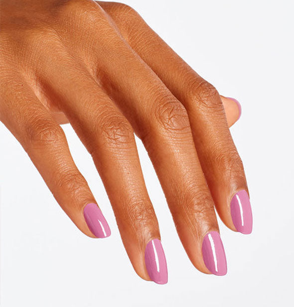 Model's hand wears a dusty, rosy-purple shade of nail polish