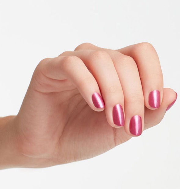 Model's hand wears a shimmery rose shade of nail polish