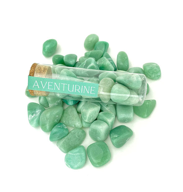 Clear vial of polished green aventurine stones with cork cap and printed green label rests on top of other loose aventurine stones