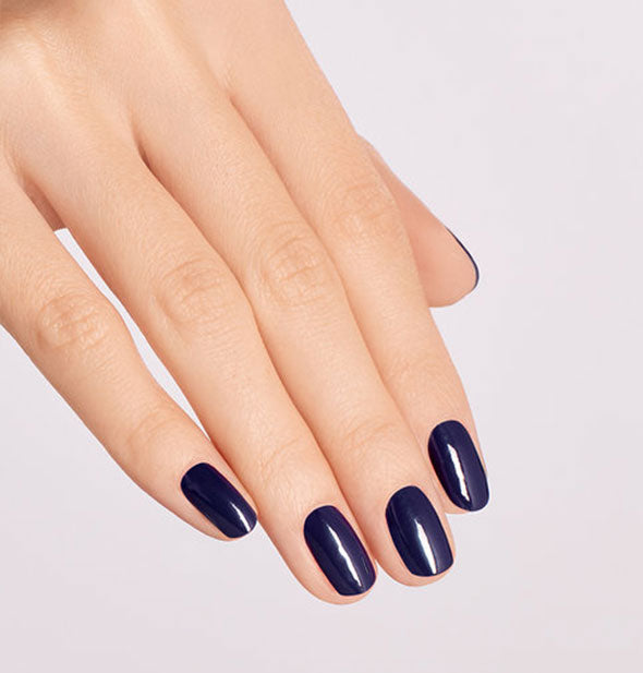Model's hand wears a very dark shade of blue nail polish