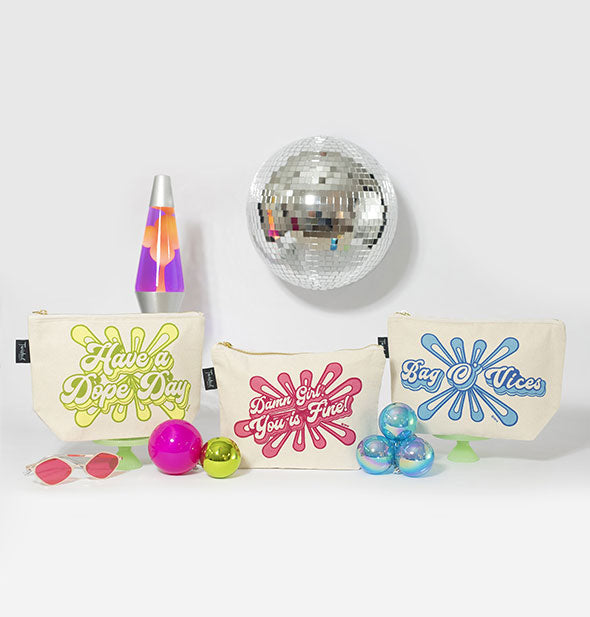 Grouping of retro-style canvas cosmetic pouches with lava lamp, disco ball, and other props