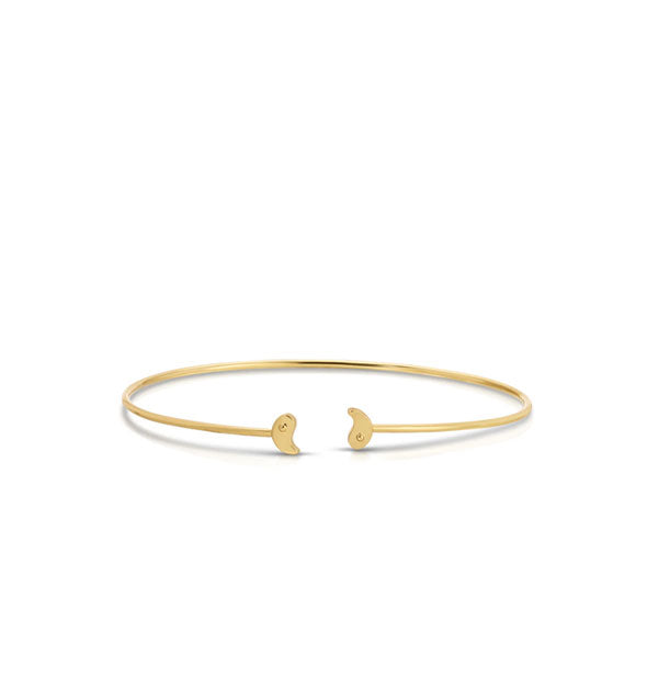 Thin gold cuff-style bracelet with two halves of a yin yang symbol on each open end