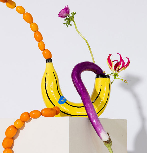 Yellow banana vase is staged with funky-looking botanicals