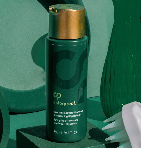 Bottle of ColorProof Baobab Recovery Shampoo sits on a green surface with other green items in the background