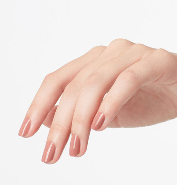 Model's hand wears a beige-pink shade of nail polish