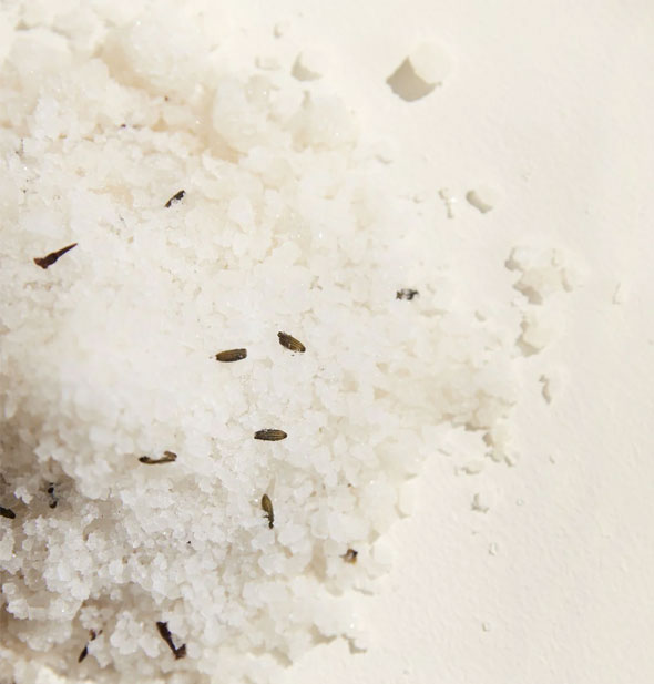 Closeup of bath salt granules with lavender buds scattered throughout