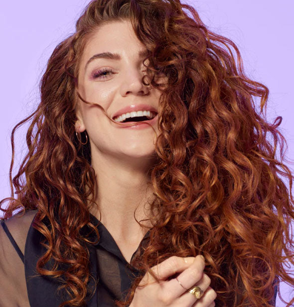 Model with curly hair demonstrates the results of styling with Bumble and bumble Curl Mousse