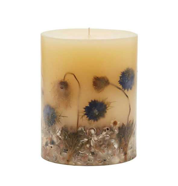 White pillar candle with dried flowers and small seashells embedded in the wax