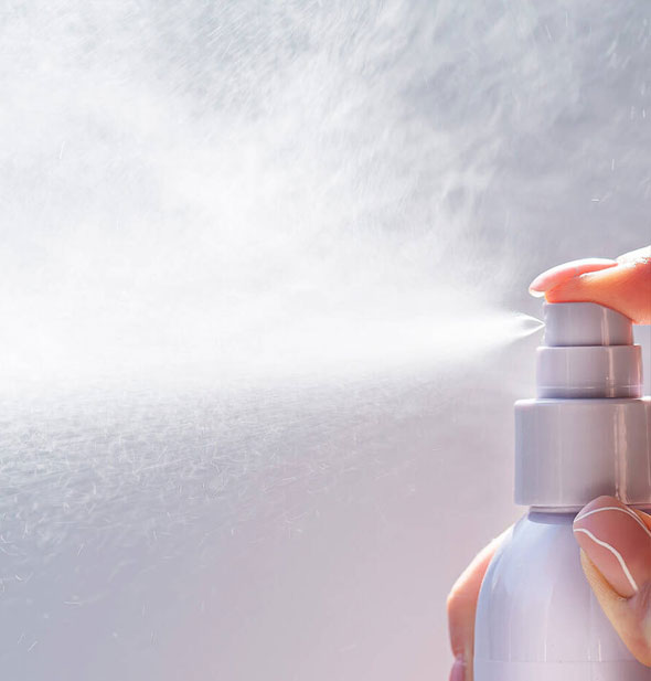 Model's hand dispenses Pureology Style + Protect Beach Waves Sugar Spray