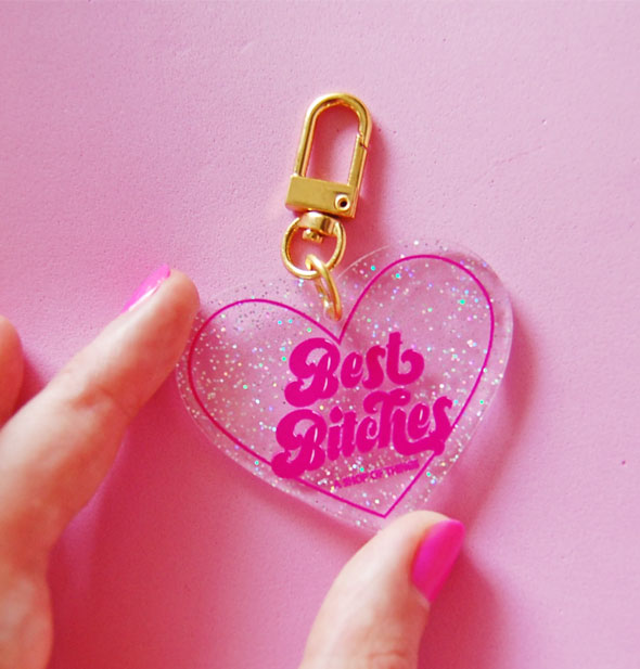Model's hand holds the Best Bitches heart-shaped keychain for size reference
