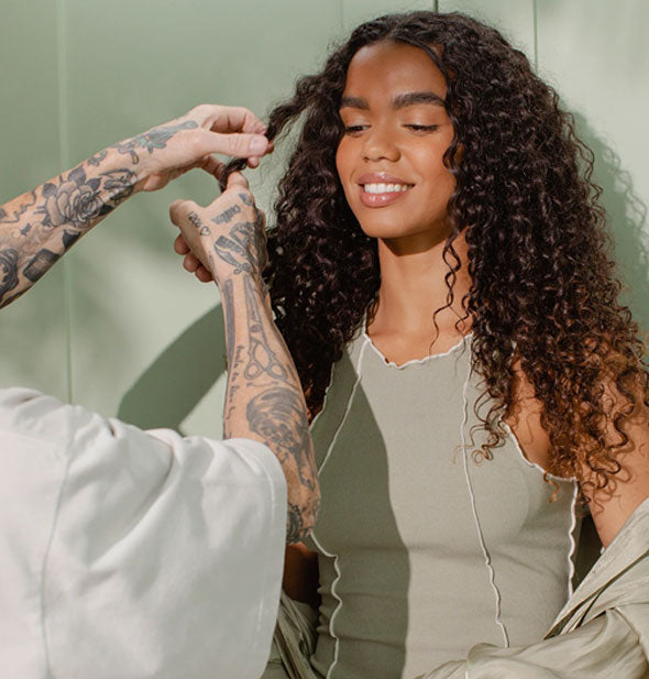 A stylist works with the very curly hair of a model/client