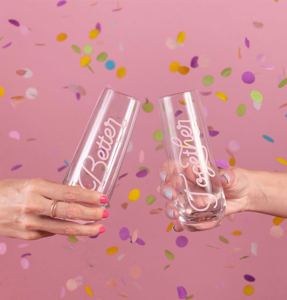 Models' hands hold stemless Better and Together champagne flutes against a pink backdrop littered with colorful confetti