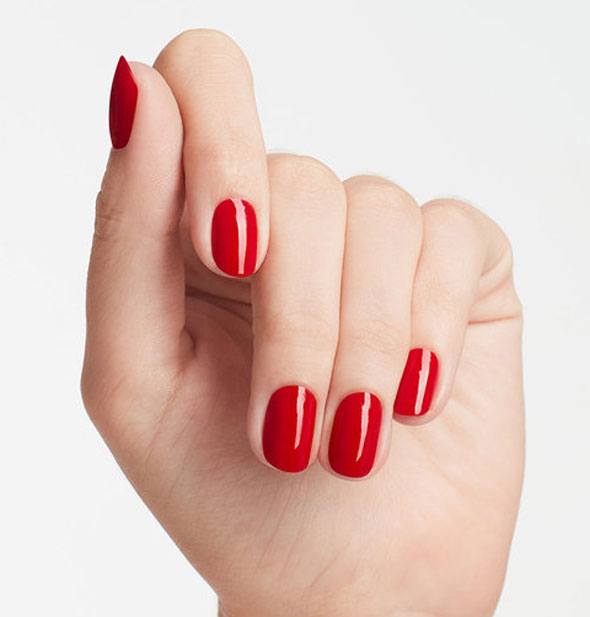 Model's hand wears a bright red shade of nail polish