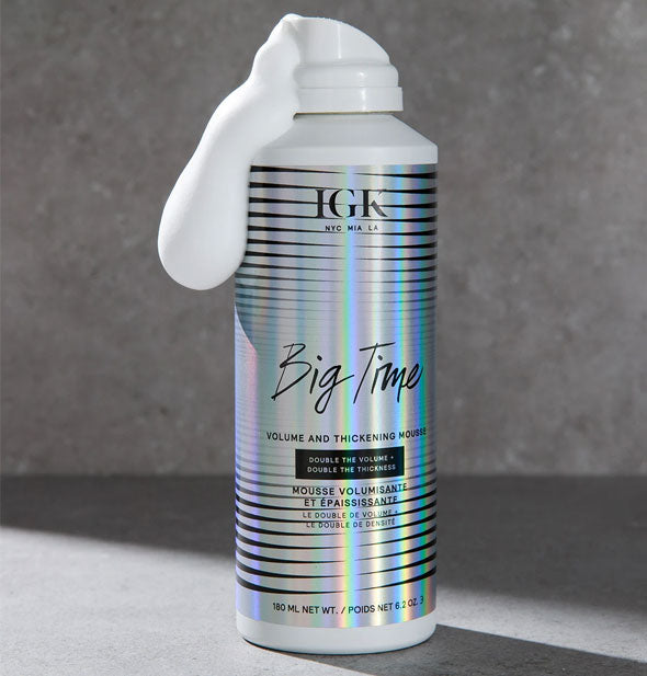 Can of IGK Big Time Volume and Thickening Mousse on a gray marble background with some foamy white product dispensed