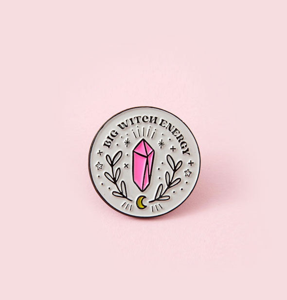 Round enamel pin features pink crystal artwork with botanical and celestial accents below the words, "Big Witch Energy"