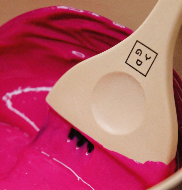 Biodegradale material Good Dye Young tint brush is dipped into a bowl of magenta hair color