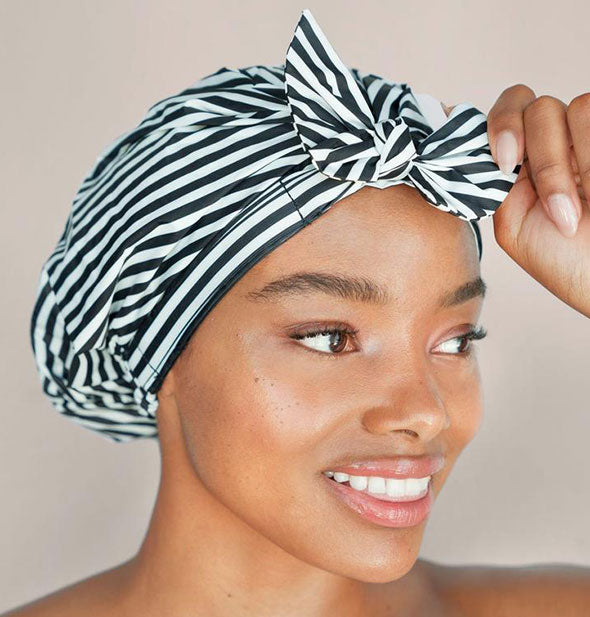 Model wears a black and white striped shower cap with bow