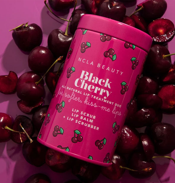 NCLA Beauty Black Cherry All Natural Lip Treatment Duo tin lays on a bed of black cherries