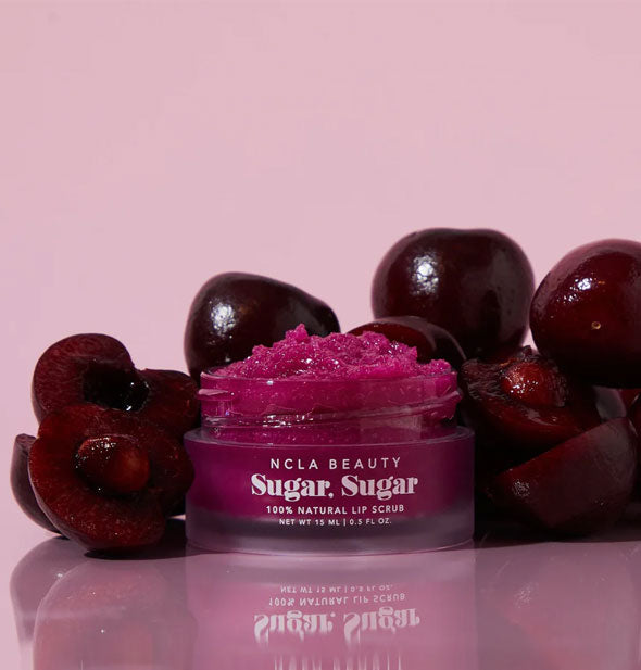Pot of purple NCLA Beauty Sugar, Sugar 100% Natural Lip Scrub flanked by black cherries