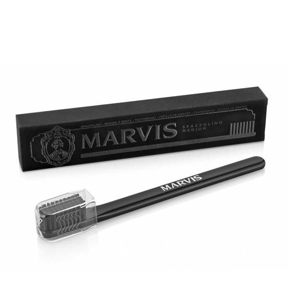 Black Marvis toothbrush with with clear plastic bristle protector sits alongside black box packaging