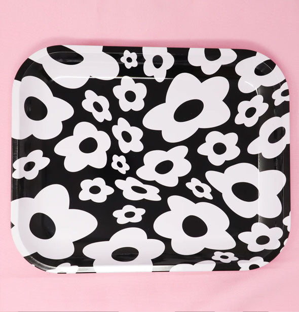 Rounded rectangular black and white floral print tray rests on a pink surface