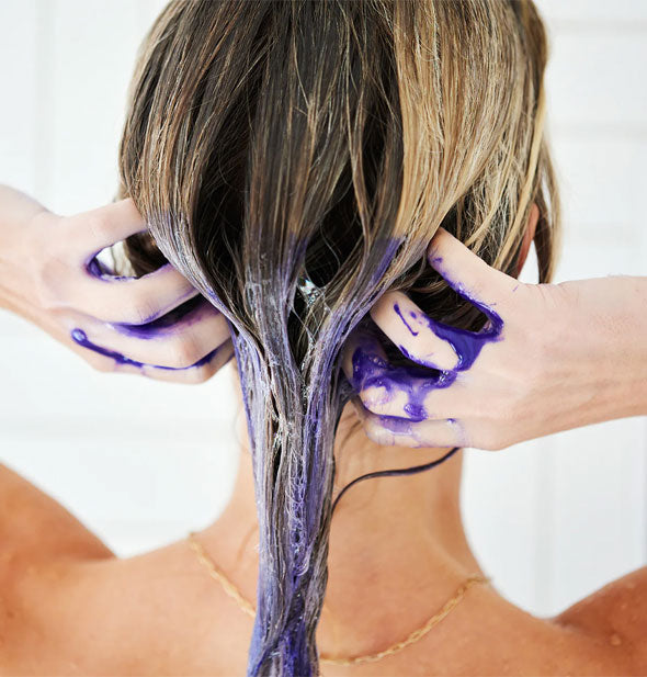 Model massages purple Unite Blonda Toning Shampoo into the bottom half of wet hair