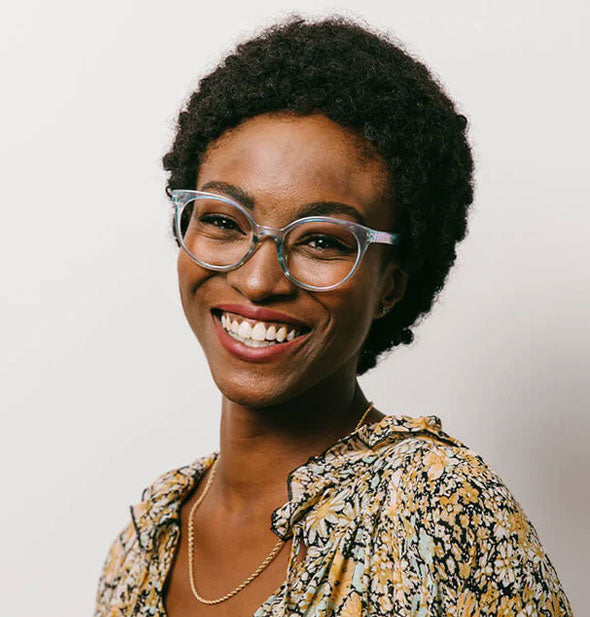 Smiling model wears a pair of rounded cat-eye glasses frames with a Blue iridescent finish