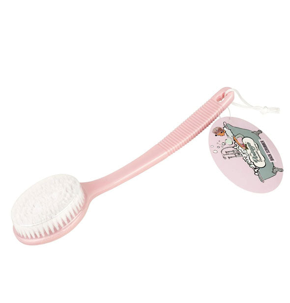 Brush with long pink handle and round paddle with white bristles has a tag with bathtub illustration attached