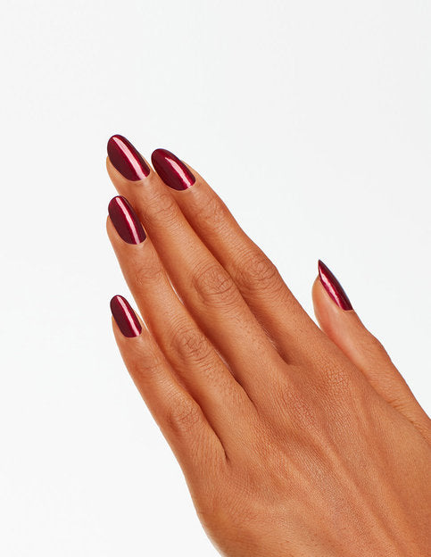 Model's hand wears a shimmery dark red shade of nail polish