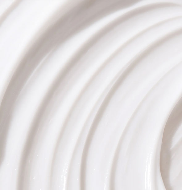 Closeup of white hair product with ridges raked through it