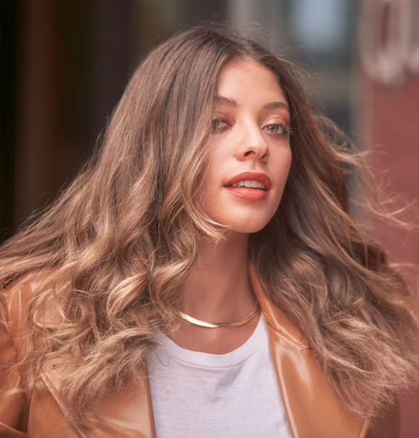 Model with healthy-looking hair styled in loose waves being blown back slightly be a breeze