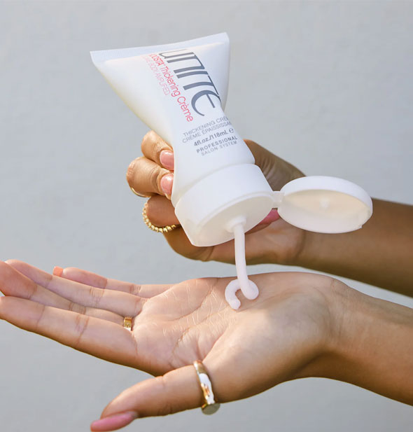 Model dispenses Unite BOOSTA Thickening Crème into palm of hand