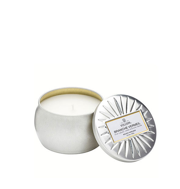 Metallic silver Branche Vermeil Voluspa tin candle with lid featuring radial embossing set to the side
