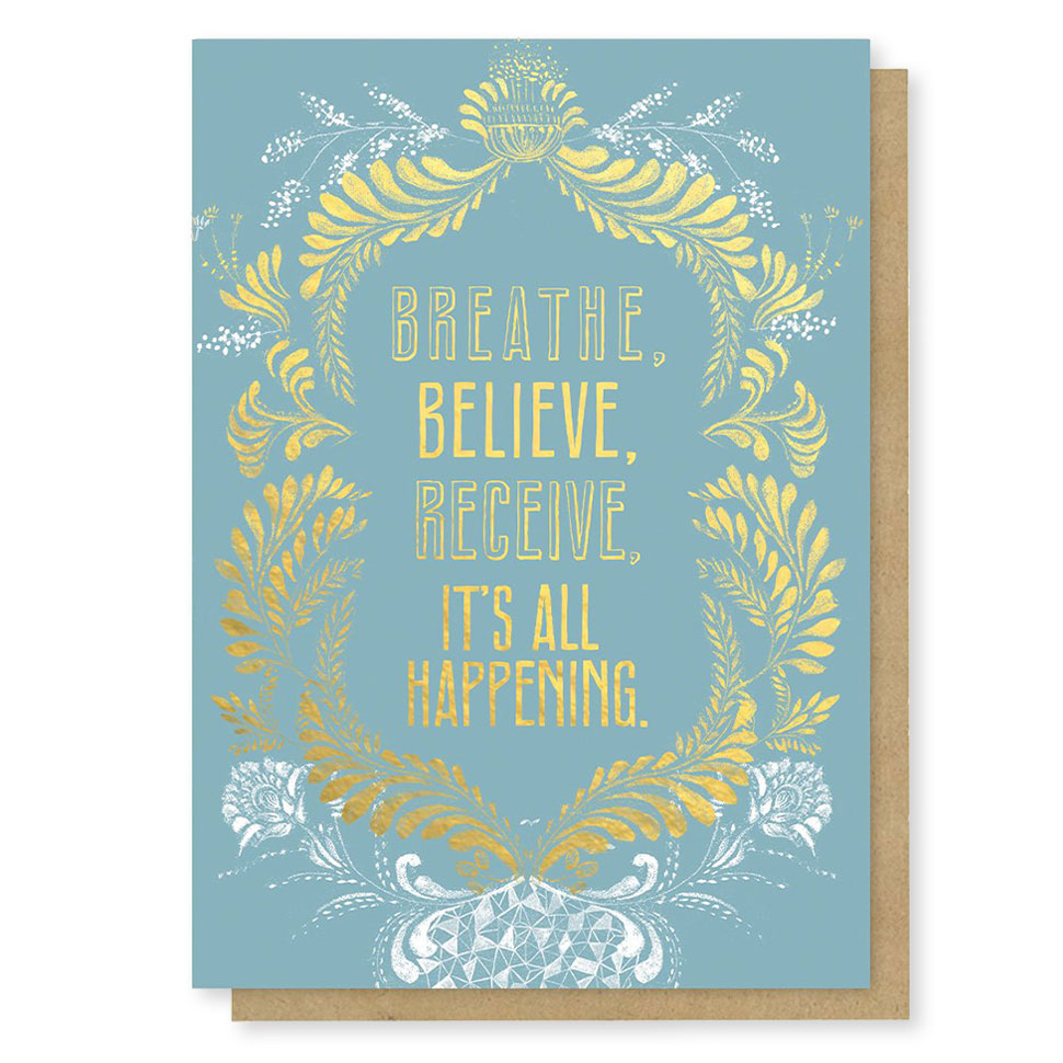 Blue greeting card with intricate white and gold flourishes says, "Breathe, believe, receive, it's all happening."