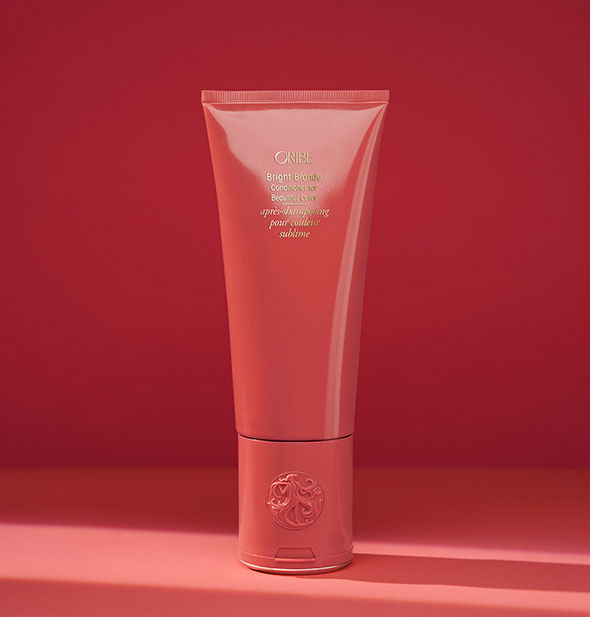 Red bottle of Oribe Bright Blonde Conditioner for Beautiful Color on red background