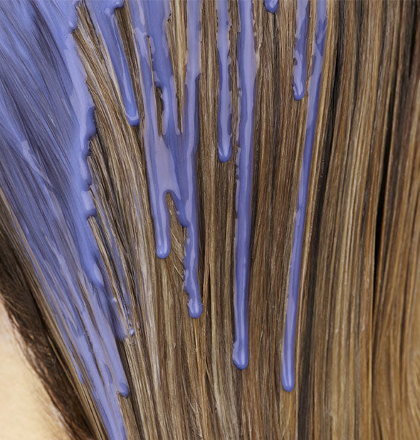 Drips of Oribe Bright Blonde Radiance & Repair Treatment running through a model's hair show product's purple pigmentation