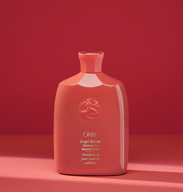 Red bottle of Oribe Bright Blonde Shampoo for Beautiful Color on red background