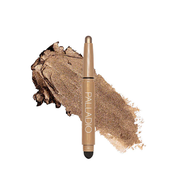 Double-ended Palladio eyeshadow stick with color at one end and black blending sponge at the other rests in front of a color swatch sample in the shade Bronze Shimmer