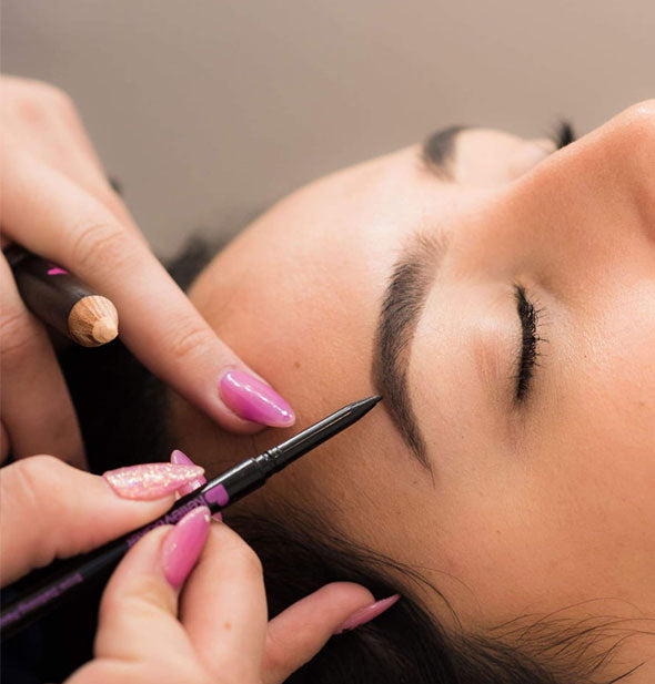 A makeup artist uses the Kelley Baker Brow Defining Pencil to enhance model's eyebrow