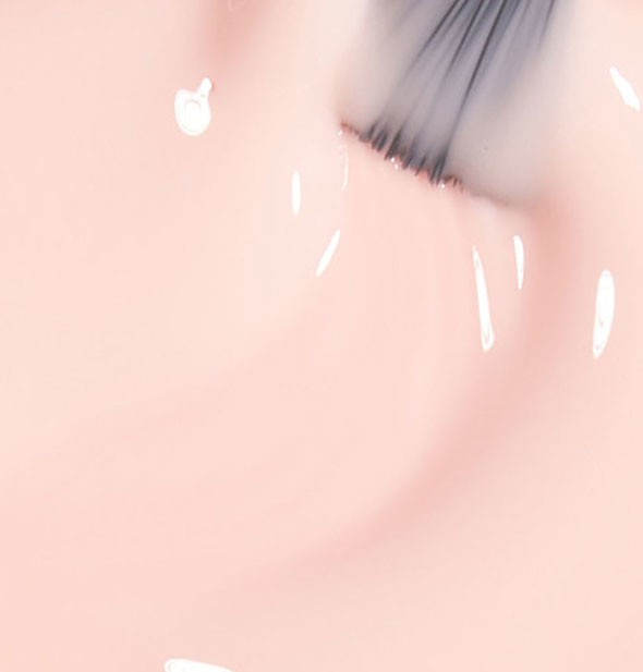 Closeup of very pale pink nail polish with a brush tip drawn through it
