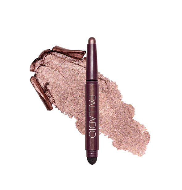 Double-ended Palladio eyeshadow stick with color at one end and black blending sponge at the other rests in front of a color swatch sample in the shade Burgundy Shimmer