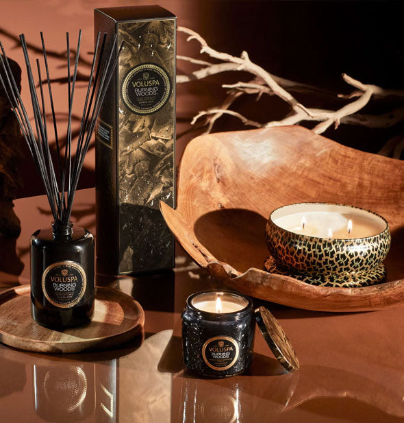 Voluspa candles and reed diffuser on polished wooden surface with other wood accoutrements