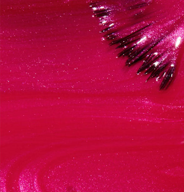 Shimmery magenta nail polish closeup with brush tip applied