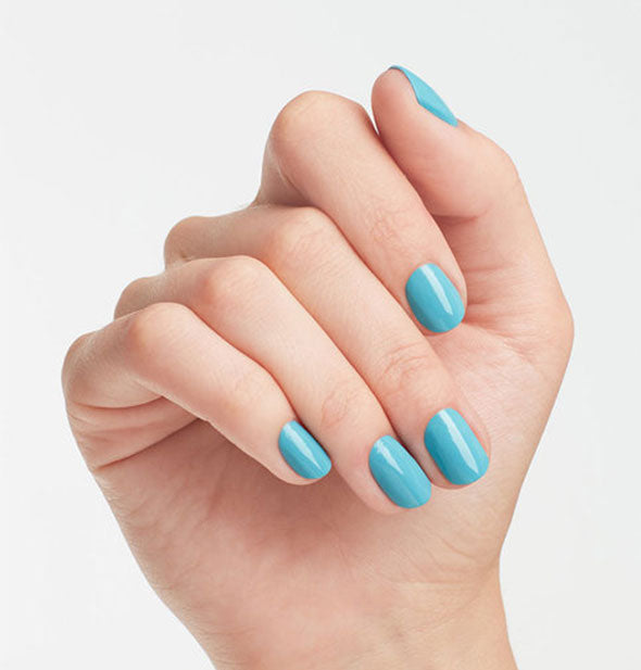 Model's hand wears a light-to-medium shade of blue nail polish