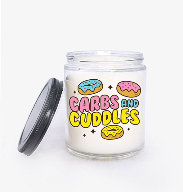 Jar candle with black metal lid set to the side says, "Carbs and Cuddles" in colorful bubble lettering with donut illustrations and stars