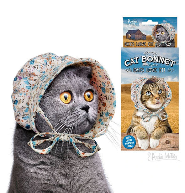 Gray cat wears a floral bonnet with drawstrings next to Cat Bonnet packaging