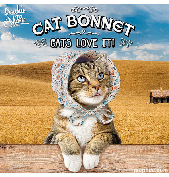A cat wearing a floral Archie McPhee brand bonnet is posed with paws over a fence slat with a prairie scene in the background; a top caption says "Cat Bonnet: Cats Love It!"