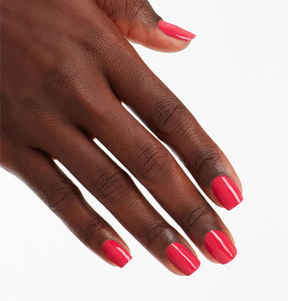 Model's hand wears a dark reddish pink shade of nail polish